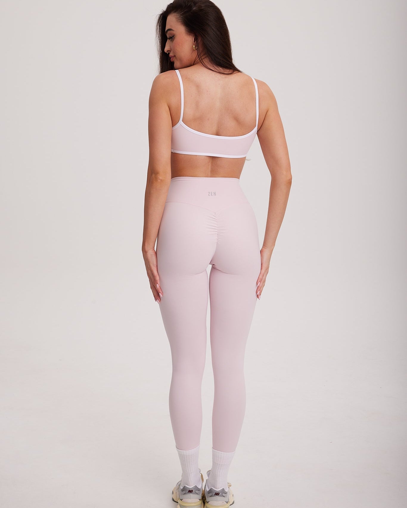 kobieta stojąca tyłem prezentująca długie legginsy z delikatnym scrunchem na pośladkach i wysokim pasem z logo Zen