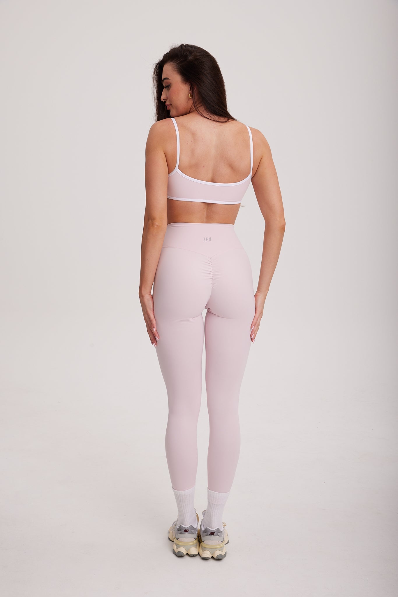 kobieta stojąca tyłem prezentująca długie legginsy z delikatnym scrunchem na pośladkach i wysokim pasem z logo Zen