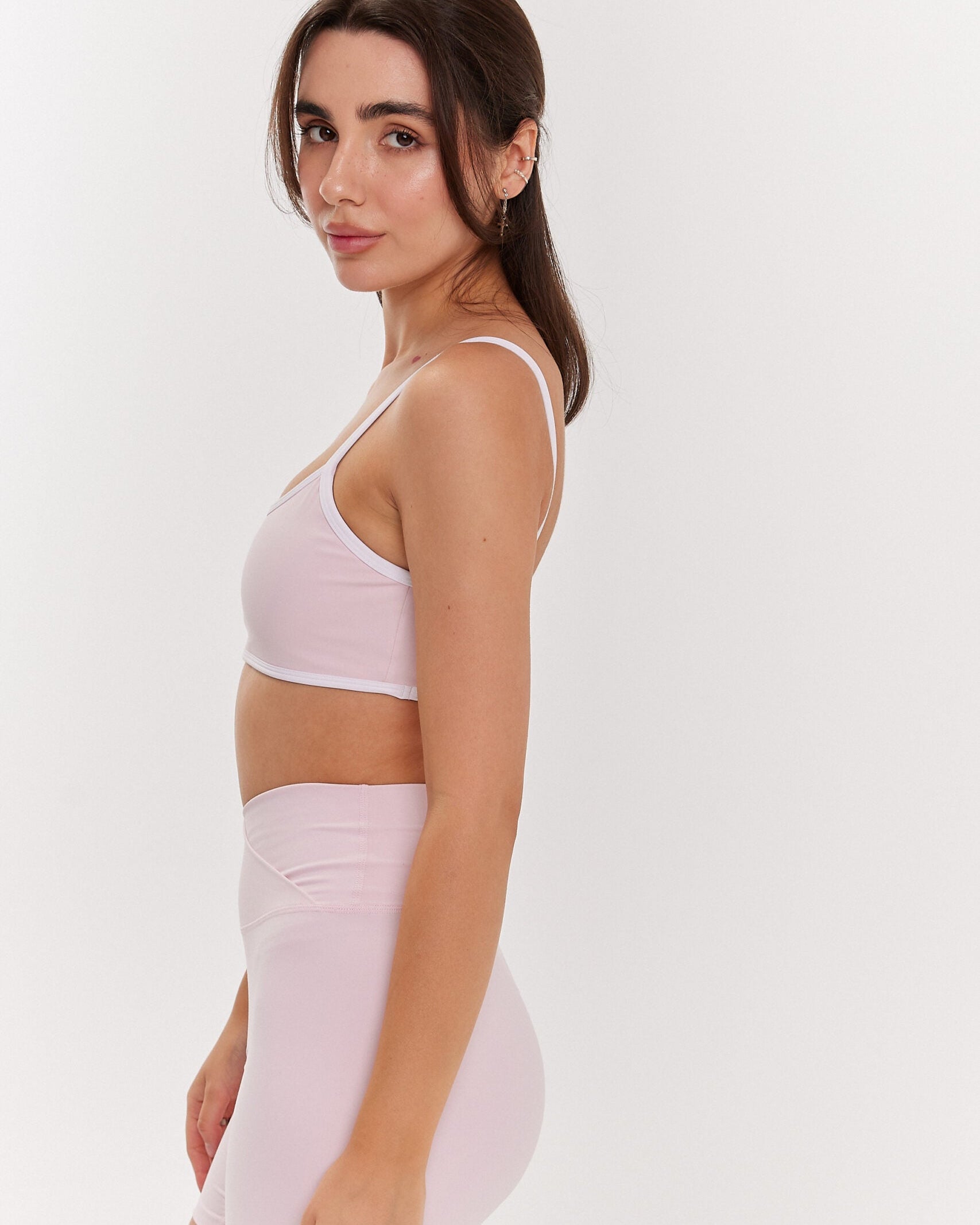 Zdjęcie kobiety bokiem różowych spodenek z zakładką i rózowego stanika z białymi ramiączkami