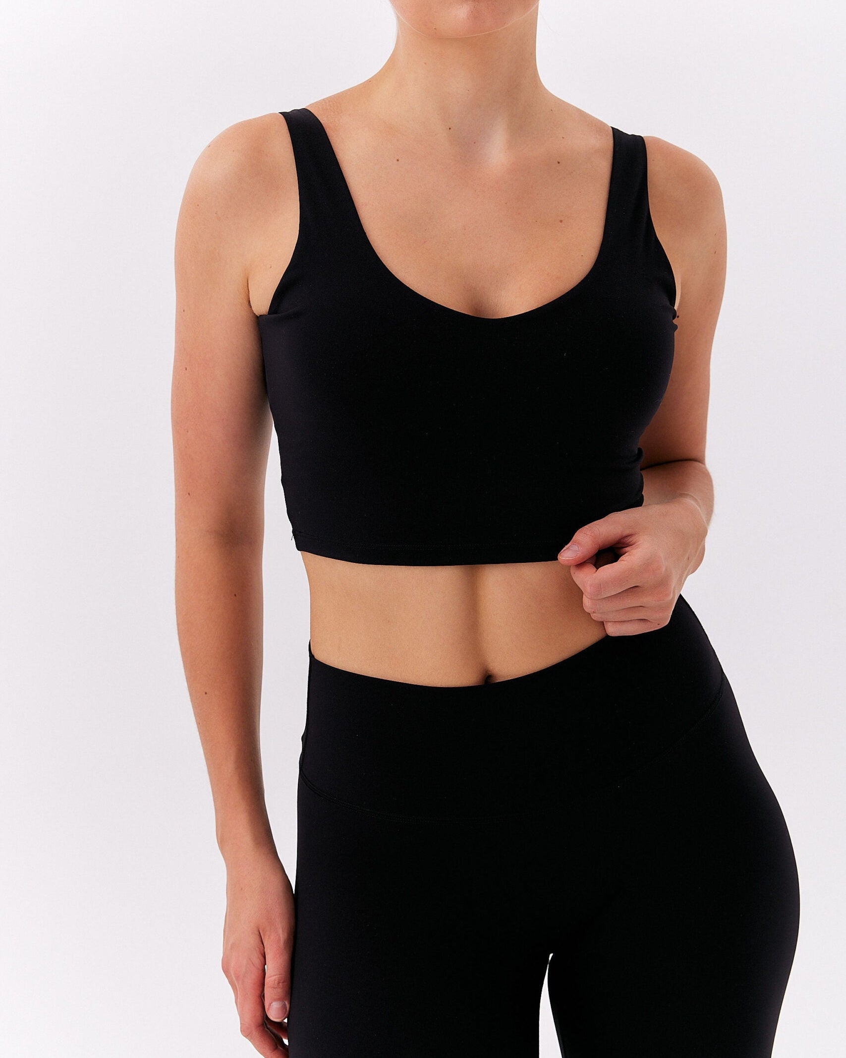 Kobieta w czarnym krótkim topie na grubych ramiączkach i wysokich leginsach