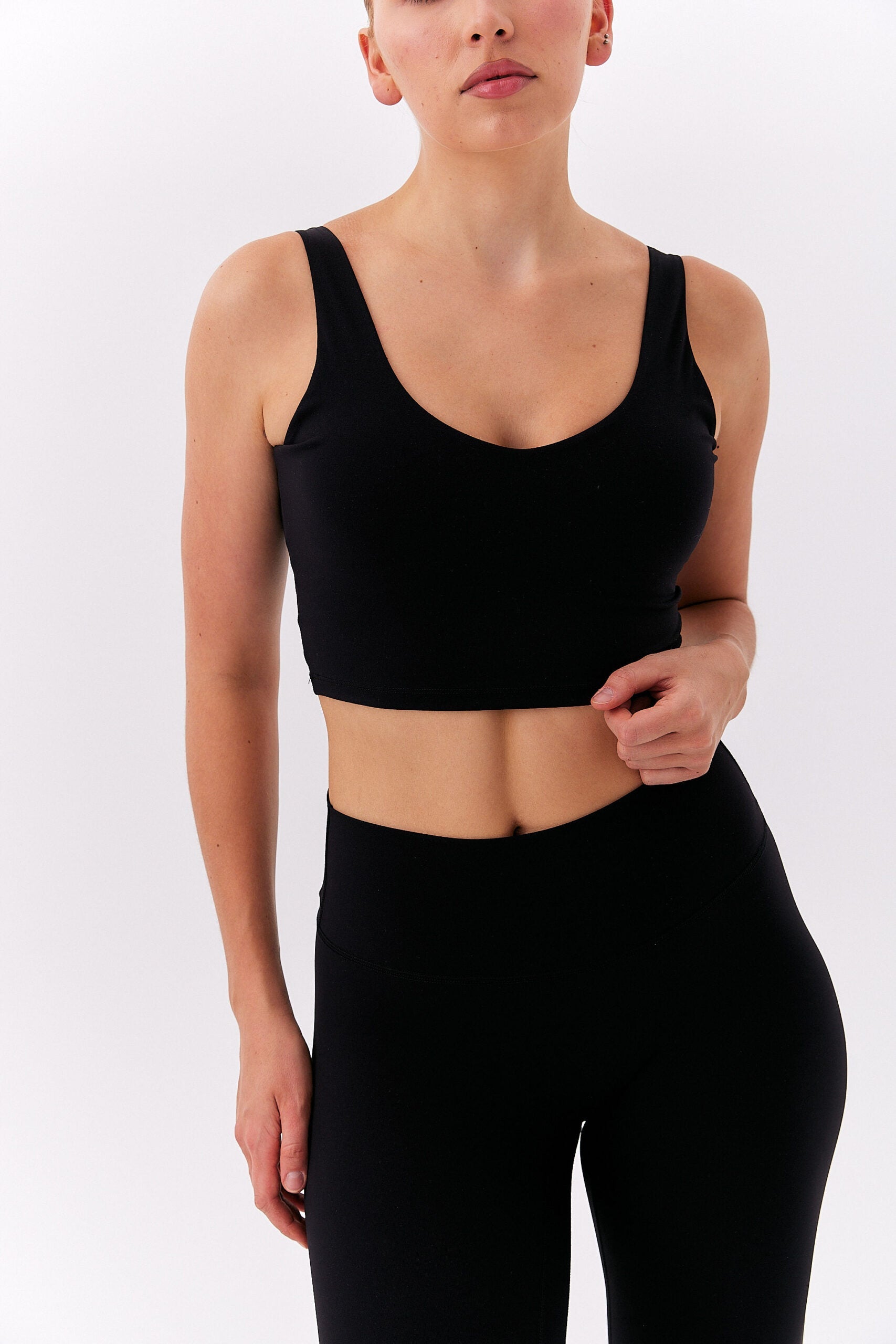 Kobieta w czarnym krótkim topie na grubych ramiączkach i wysokich leginsach