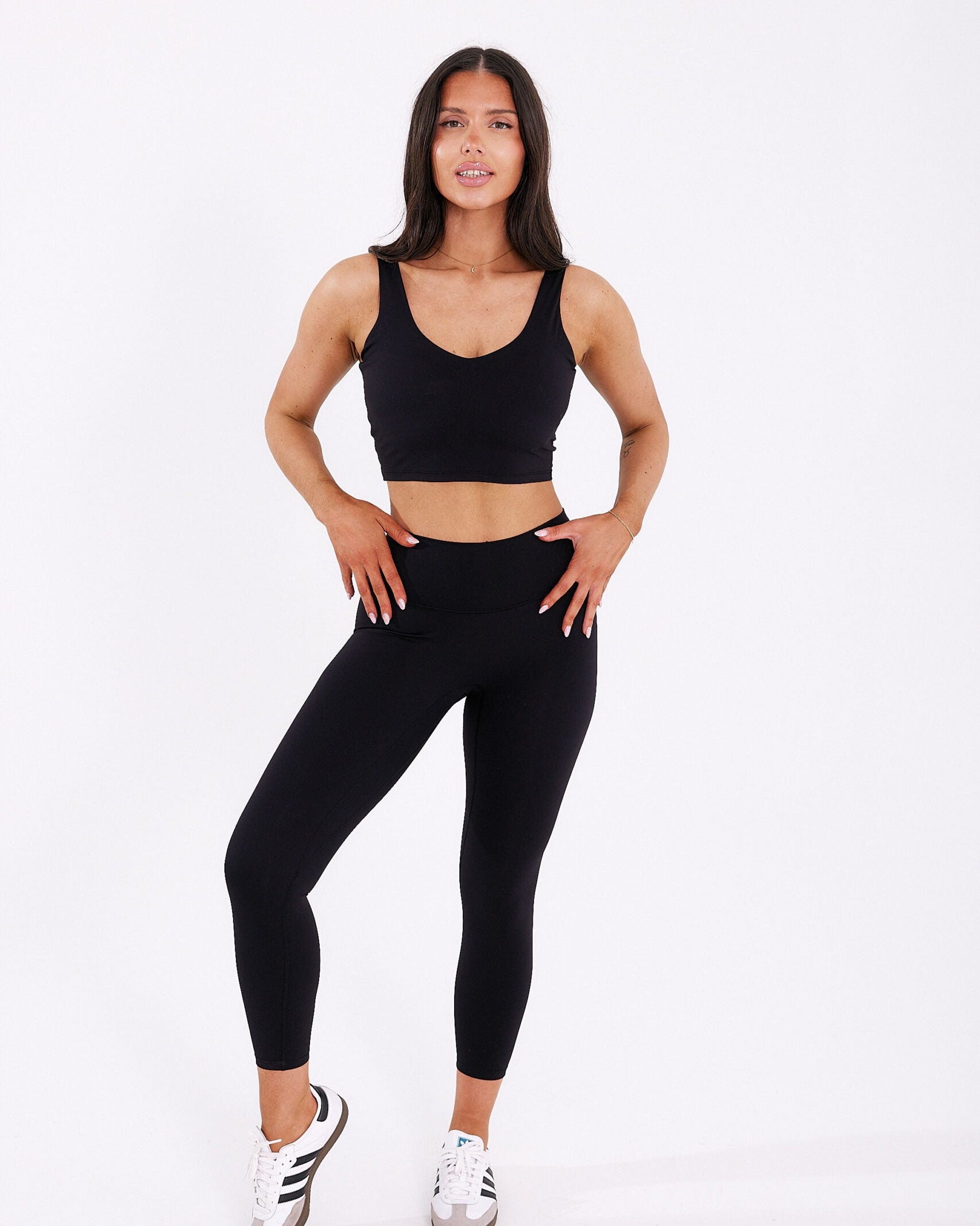 Opalona kobieta w czarnym krótkim tank topie Zen i długich prostych leginsach