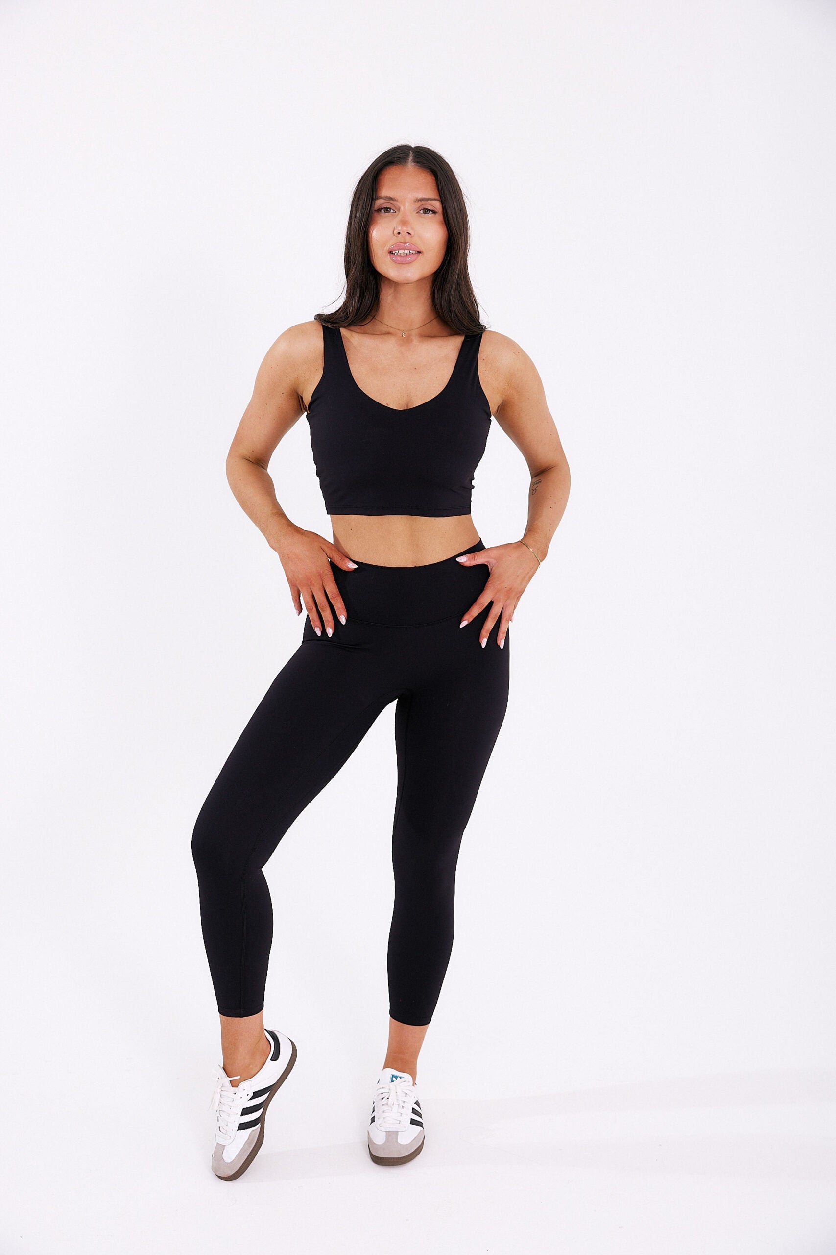 Opalona kobieta w czarnym krótkim tank topie Zen i długich prostych leginsach