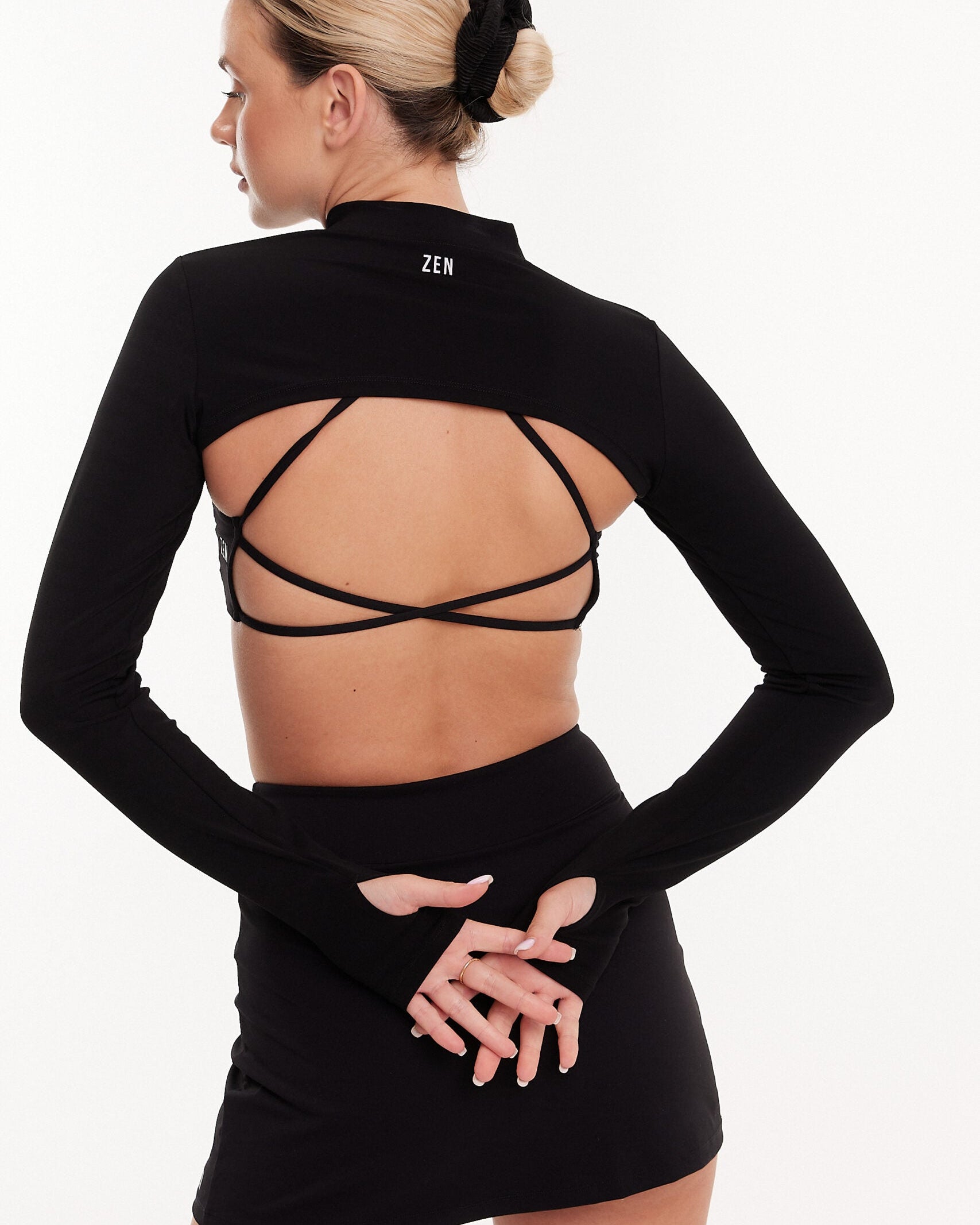 Kobieta stojąca tyłem prezentująca odkryte plecy stanika o cienkich krzyżowanych ramiączkach